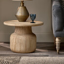 Mango wood side table with a grooved texture, holding a lamp and a glass